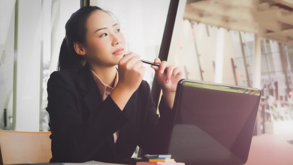 Woman thinking at her desk and holding a pen